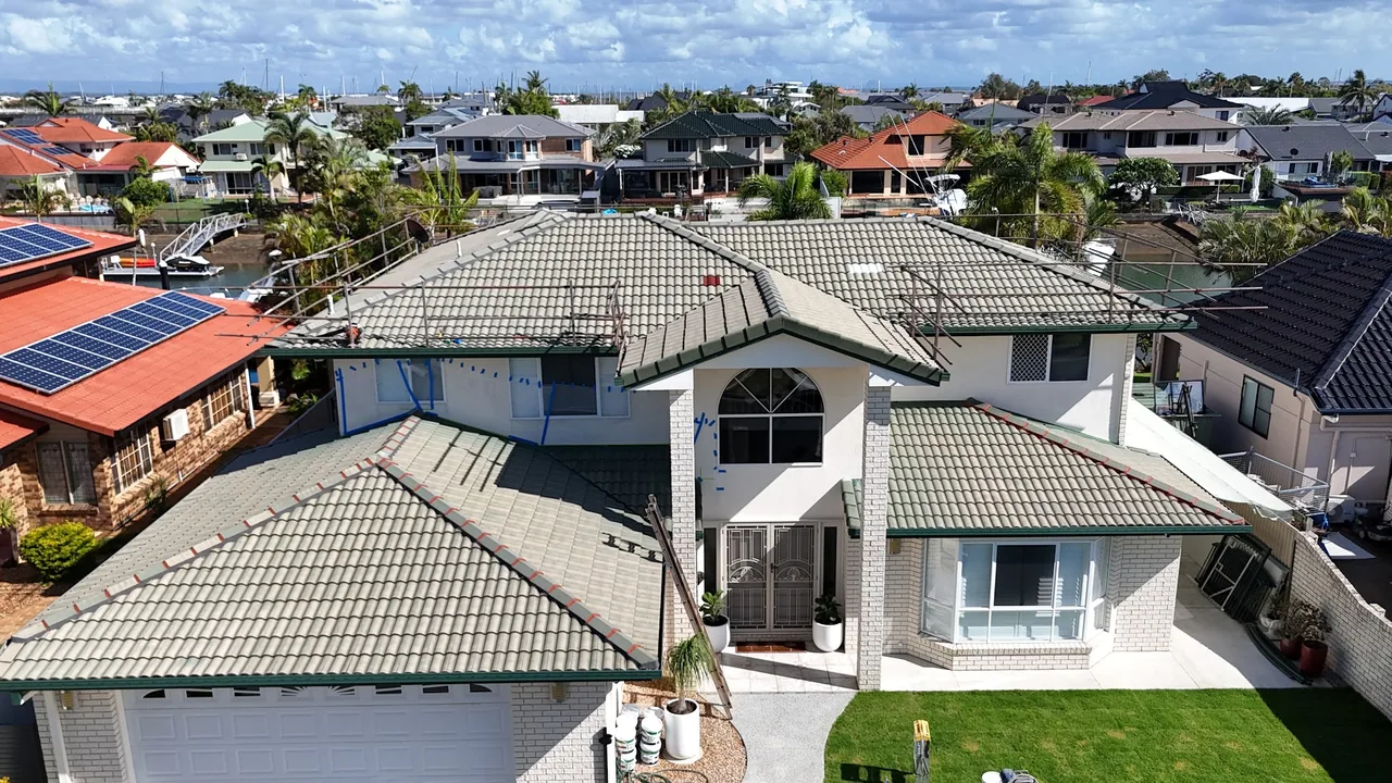 Freshly recoated charcoal tile roof on a waterfront home, side aerial view